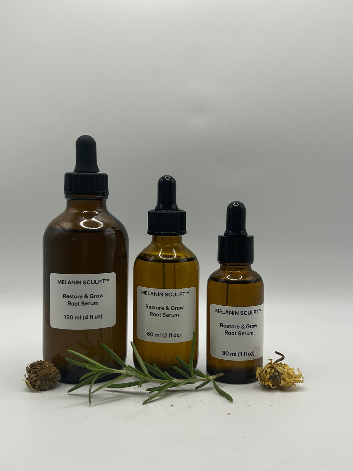 Restore & Grow Root Serum in 4 fl oz, 2 fl oz, and 1 fl oz amber dropper bottles with rosemary and dried botanicals